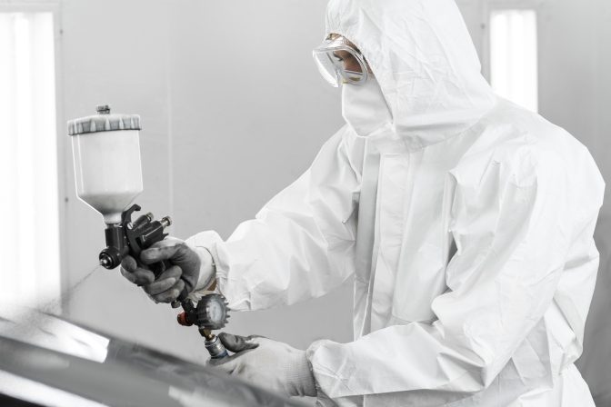 man-hazmat-suit-using-gun-paint-car-shop